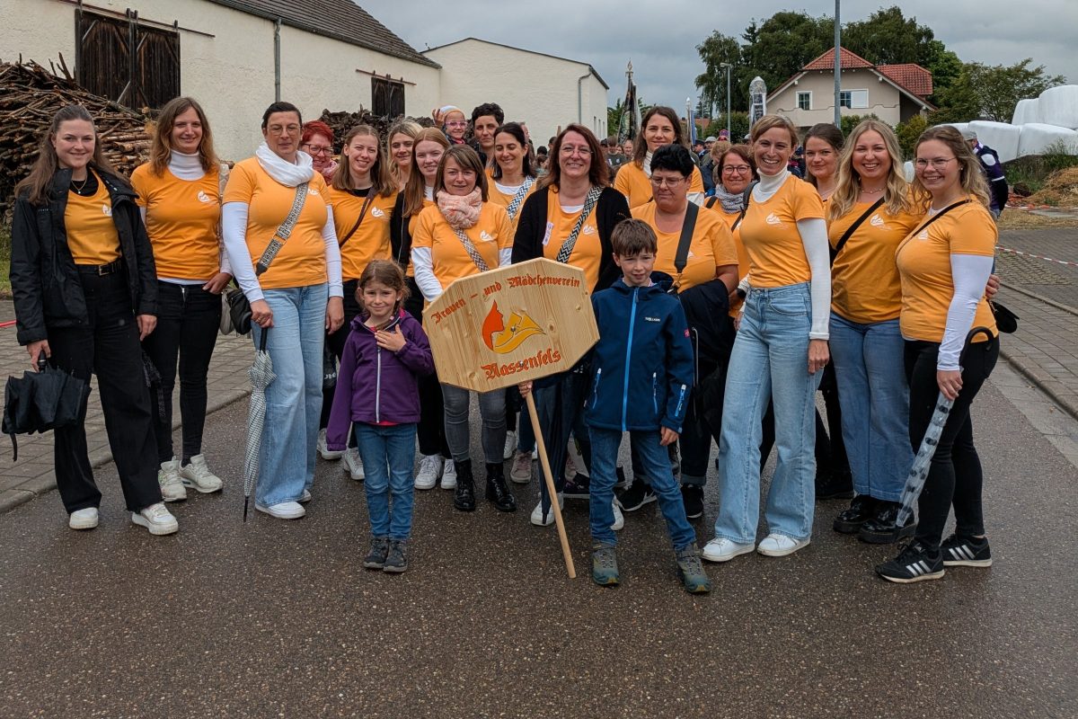 Mitglieder des Frauen- und Mädchenvereins in orangefarbenen Vereins-T-Shirts mit dem Vereinsschild beim Festumzug in Wolkertshofen